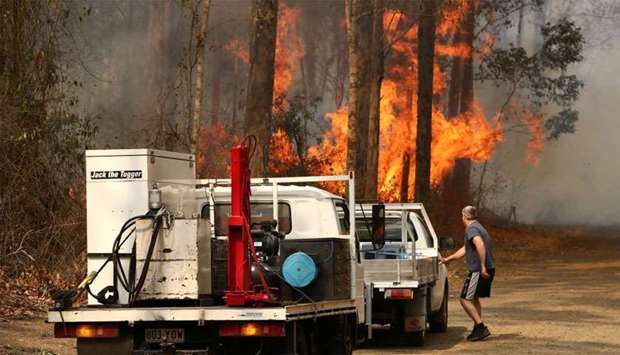 A local resident is seen near a bushfire burning next to Busbys Flat Road in Busbys Flat