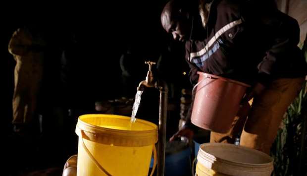 Residents collect water at night from an electric-powered borehole, as the country faces 18-hour daily power cuts, in a suburb of Harare, Zimbabwe, July 30, 2019.