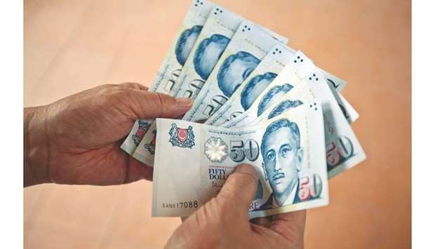 Singapore dollar banknotes are arranged for a photograph in Singapore (file). The currency is set to weaken because the central bank is likely to scrap its appreciation bias at a policy meeting next week, according to a growing group of forecasters.