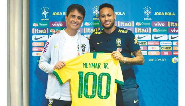 Brazilian football star Neymar (R) receives a jersey with the number u2018100u2019 from former star Bebeto during a press conference in Singapore yesterday. Neymar will be playing his 100th match for Brazil today.
