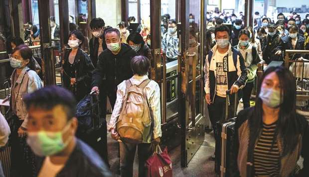 People wearing facemasks arrive at the Beijing Railway station after the countryu2019s national u201cGolden Weeku201d holiday in Beijing, yesterday.