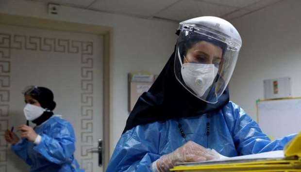 A nurse wearing a protective suit and mask checks the files at Hazrate Ali Asghar Hospital.