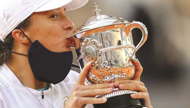 Polandu2019s Iga Swiatek kisses the Suzanne Lenglen trophy after beating Sofia Kenin (below) of the US in the French Open final at Roland Garros in Paris, France, yesterday. (AFP)