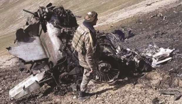 A man stands by the remains of an Armenian SU-25 warplane reportedly downed during fighting with Azerbaijan over the breakaway Nagorny Karabakh region.
