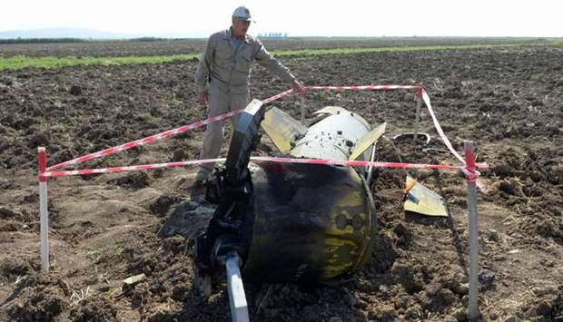 A man stands by what is said is the remains of a Tochka U missile in a field in Fizuli district, Azerbaijan
