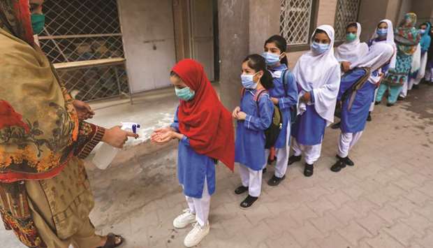 Students wear protective masks as they get their hands sanitised before entering a class after the provincial government allowed reopening of both primary and lower secondary classes amid the coronavirus pandemic, in Peshawar yesterday.