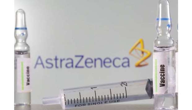 A test tube labelled with the Vaccine is seen in front of AstraZeneca logo in this illustration take
