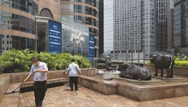 Workers sweep the area next to sculptures of water buffaloes outside the Exchange Square complex in Hong Kong, which houses the Hong Kong Stock Exchange. The Hang Seng index closed 2.2% up at 24,649.68 points yesterday.
