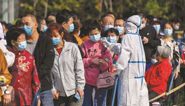 A health worker checks the temperature of residents as they line up to be tested for the Covid-19 coronavirus in Qingdao, in Chinau2019s eastern Shandong province, yesterday.