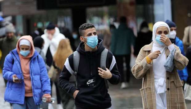 People wear protective masks as they walk, amid the outbreak of the coronavirus disease, in London, Britain