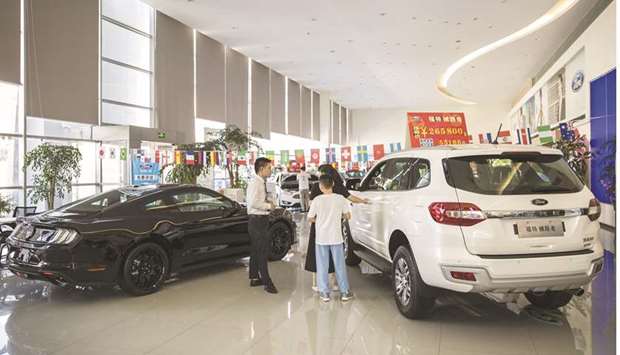 A customer speaks with a sales agent while standing between a Ford Motor Everest sport utility vehicle  (right) and a Mustang sports car on display at a Ford dealership in Shanghai. Demand for cars in China is going from strength to strength, making the automobile market in Asiau2019s biggest economy a lone bright spot as the coronavirus  pandemic puts a damper on sales in Europe and the US.