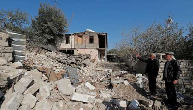 Men stand next to the ruins of a house that was destroyed by recent shelling during the military conflict over the breakaway region of Nagorno-Karabakh, in the town of Martuni