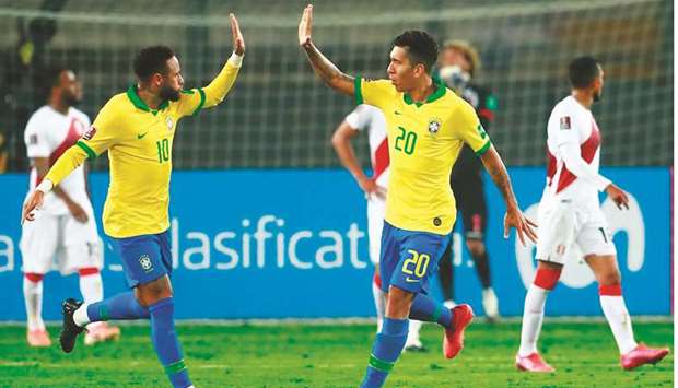 Brazilu2019s Neymar (left) celebrates with teammate Roberto Firmino after scoring against Peru during the 2022 FIFA World Cup South American qualifiers in Lima. (AFP)