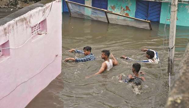 Residents wade through a waterlogged alley after heavy rainfall in Hyderabad yesterday.