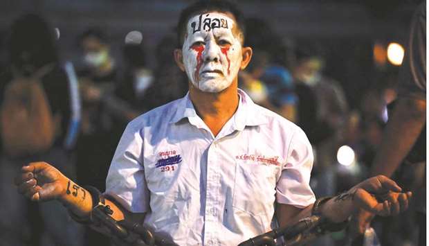 A pro-democracy protester in chains and make-up is seen during a demonstration at a road intersection in Bangkok.