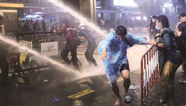 People are hit with water from water cannons during anti-government protests, in Bangkok, yesterday.
