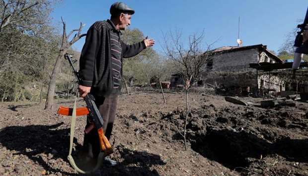 Local resident Alexei Agadzhanov holds a rifle while showing a crater following recent shelling in the settlement of Shosh in the course of a military conflict over the breakaway region of Nagorno-Karabakh