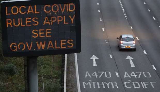 Traffic passes a COVID-19 sign displayed along the M4 motorway in southeast Wales as further restrictions come into force as the number of novel coronavirus COVID-19 cases rises.