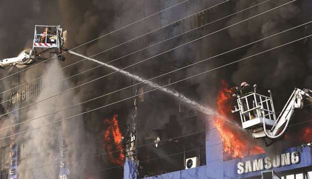 DAMAGE-CONTROL: Firefighters try to extinguish a fire that broke out in a four-storey commercial building that houses mobile, laptop and electronics plaza in Lahore yesterday. (AFP)