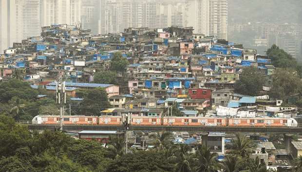 A metro train moves past slums and buildings in Mumbai yesterday. The Mumbai Metro rail network resumed services after nearly seven months due to the coronavirus pandemic.