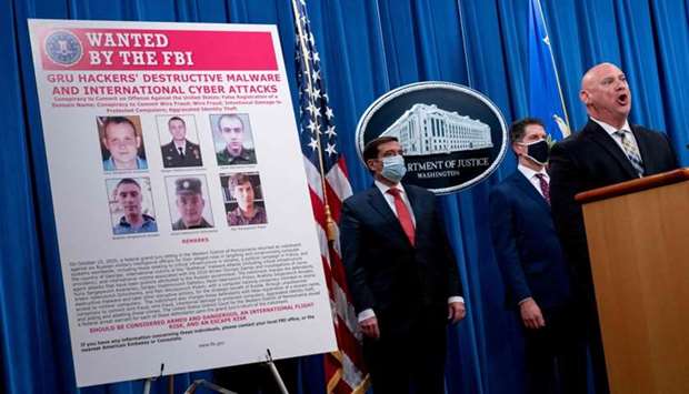 A poster showing six wanted Russian military intelligence officers is displayed as FBI Special Agent in Charge of the Pittsburgh field office Michael Christman(R), accompanied by Assistant Attorney General for the National Security Division John Demers(L), and FBI Deputy Director David Bowdich, speaks at a news conference at the Department of Justice yesterday in Washington, DC. Six Russian military intelligence officers have been charged with carrying out cyberattacks on Ukraine's power grid, the 2017 French elections and the 2018 Winter Olympics, the US Justice Department announced.