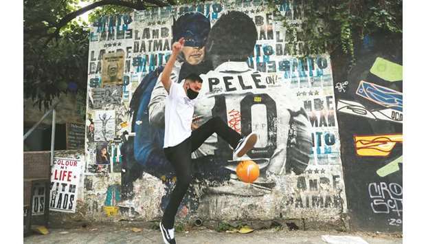 Silvio Cesar Martins plays football near a mural depicting Brazilian soccer legend Pele kissing the face of the comic superhero Batman in Sao Paulo. (Reuters)