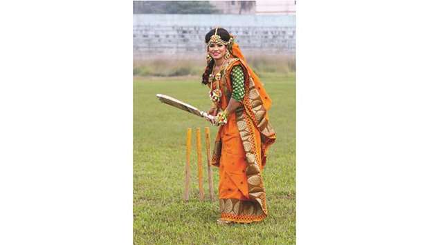 Bangladeshu2019s cricketer Sanjida Islam bats as she poses for a photograph with a traditional wedding dress after her marriage ceremony, in Rangpur Stadium. (AFP)