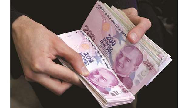 A merchant counts Turkish lira banknotes at the Grand Bazaar in Istanbul (file). Turkeyu2019s central bank bucked expectations for a big interest rate hike yesterday and sent the lira falling to a record low by holding its policy rate at 10.25% and saying it had already made progress in containing inflation.