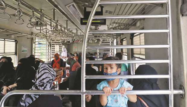 A girl holds onto a railing in a suburban train as she travels with a relative after authorities resumed the train services for women passengers during non-peak hours, amidst the coronavirus disease outbreak, in Mumbai on October 21.