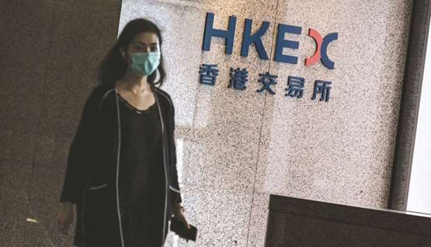 An employee wearing a protective mask walks past a signage for Hong Kong Exchanges & Clearing Ltd displayed at the Exchange Square complex in Hong Kong. The Hang Seng closed 0.1% up at 24,786.13 points yesterday.