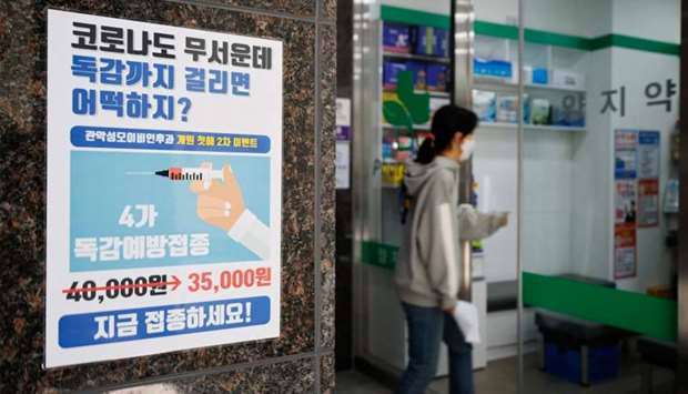 A woman walks past a poster encouraging people to get an influenza vaccine in Seoul
