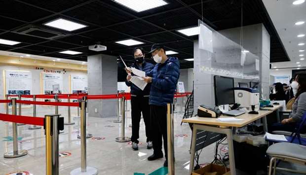 Men check a mandatory document to get an influenza vaccine at a branch of the Korea Association of Health Promotion in Seoul, South Korea