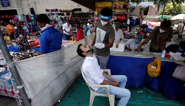 A healthcare worker takes swab from a man for a rapid antigen test in a market area, amidst the Covid-19 pandemic in Ahmedabad, India
