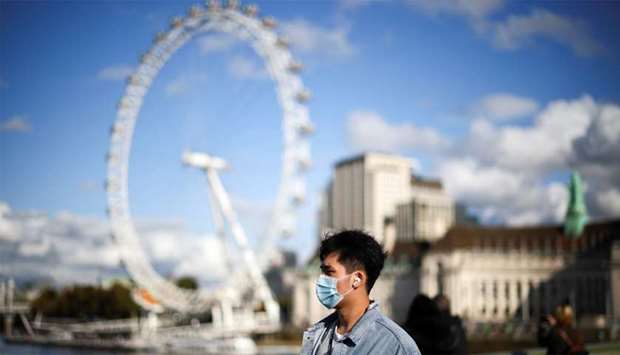 A man wearing a protective face mask walks across Westminster bridge, during the coronavirus disease (COVID-19) outbreak, in London