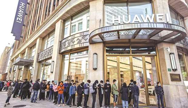 People wearing masks wait in line in front of Huaweiu2019s flagship store for pre-sales of the newly launched Huawei Mate40 mobile phone series in Shanghai yesterday. Huaweiu2019s revenue growth slowed significantly in the first nine months of 2020, the Chinese telecom giant said, citing u201cintense pressureu201d on operations during the coronavirus and as the US moves to cut off its access to vital components.