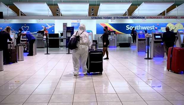 In this file photo taken on October 21, 2020 a woman in a full hazmat suit checks in for her flight at Baltimore Washington International Airport in Baltimore, Maryland, during the Coronavirus pandemic