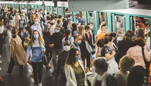 Commuters wearing protective face masks boarding and exiting a train at Saint-Lazare metro railway station in Paris. Investors banking on a coronavirus vaccine to save the world economy in 2021 need to temper their ambitions as scientists increasingly warn of a long and difficult road ahead.