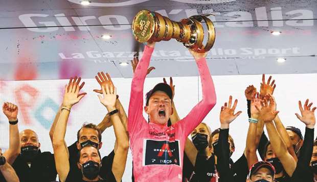 Team Ineos rider Tao Geoghegan Hart (centre) of Great Britain holds the Trofeo Senza Fine (Never ending trophy) as he celebrates on podium after winning the Giro du2019Italia in Milan, Italy, yesterday. (AFP)
