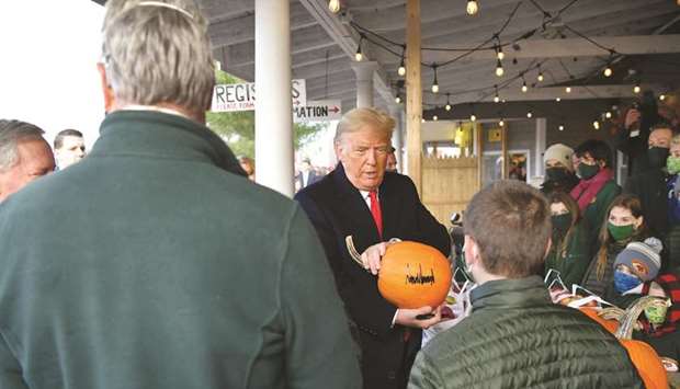 US President Donald Trump signs some pumpkins as he meets with people at Treworgy Orchards during a campaign stop in Levant, Maine, yesterday. In a single day, he covered more than 3,000km aboard Air Force One, hitting three different campaign rallies from the countryu2019s south to the midwest.
