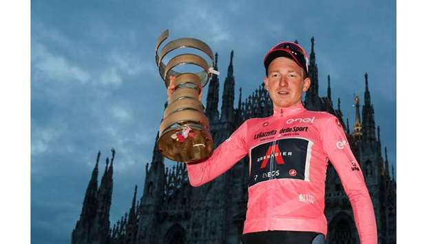 Team Ineos rider Great Britainu2019s Tao Geoghegan Hart wearing the leaderu2019s pink jersey holds the u2018Never ending trophyu2019 (Trofeo Senza Fine) as he celebrates on podium in front of the Duomo cathedral, after the the 21st and final stage of the Giro du2019Italia 2020 cycling race. (AFP)