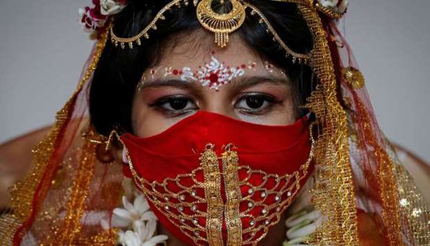 Sarayna Biswas, 6, wearing a face mask and dressed as Kumari wearing gold, takes part in a ritual during the Durga Puja festival celebrations at a pandal, or a temporary platform, amidst the outbreak of the coronavirus disease, in Kolkata, India