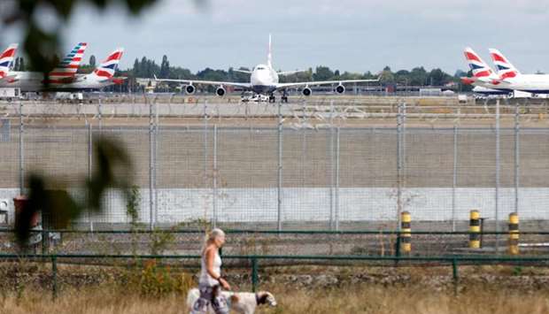 A woman walks her dog past a British Airways Boeing 747 G-CIVD plane at London Heathrow airport, one of 31 jumbo jets to be retired early by the airline due to the coronavirus disease pandemic, in London, Britain August 18