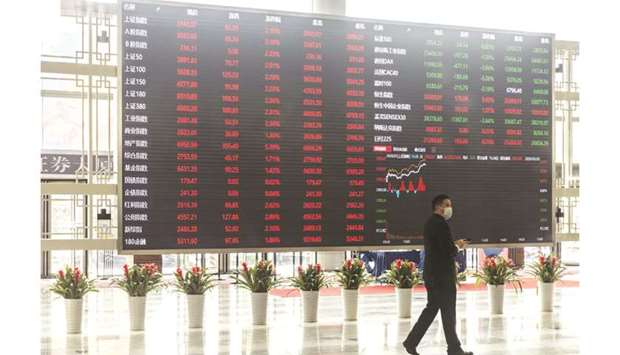 A man wearing a protective mask walks past an electronic stock board at the Shanghai Stock Exchange. The Composite index closed up 0.5% to 3,269.24 points yesterday.