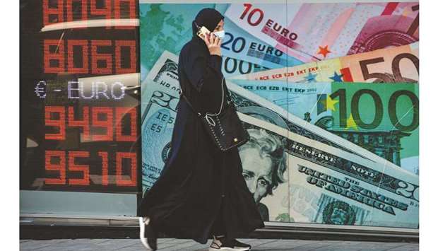 A woman walks past an information screen displaying rates in front of an exchange office in Istanbul on October 26. Turkeyu2019s central bank raised its 2020 inflation forecast more than 3 percentage points to 12.1% yesterday, saying higher import costs due to a record-weak lira were the main factor driving its upward revision.