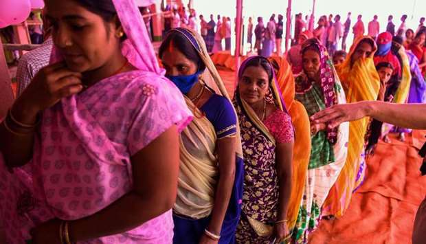 Voters queue up to cast their ballots for Bihar state assembly elections at a polling station in Masaurhi.