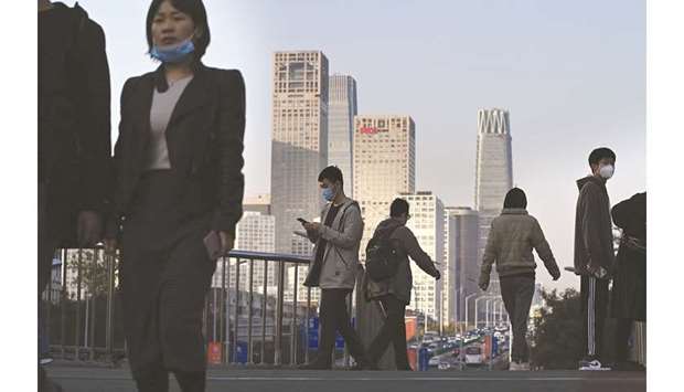 People walk on a pedestrian overpass in Beijing on October 29. Chinau2019s economy plunged 6.8% in the first quarter because of the Covid-19 outbreak, but it has recovered and looks set to be the only major economy to achieve growth this year.