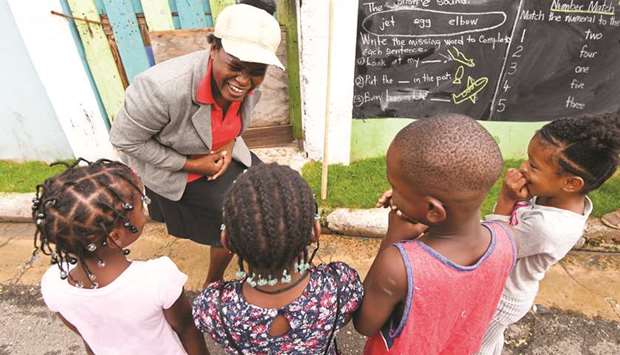 Educator Taneka Mckoy teaches a lesson with a blackboard painted on a wall, in a low-income neighbourhood in Kingston.