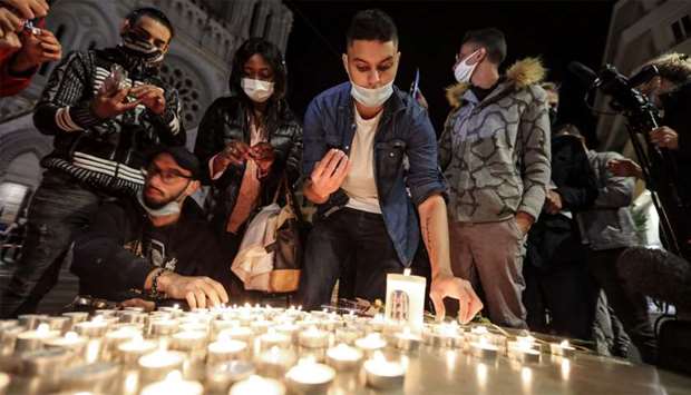 People lights candle outside the Notre-Dame de l'Assomption Basilica in Nice in tribute to the three victims of a knife attacker