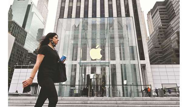 A person walks past the Apple store on Fifth Avenue in New York City (file). The late launch of new 5G phones caused Appleu2019s customers to put off buying new devices, leading the company on Thursday to report the steepest quarterly drop in iPhone sales in two years.