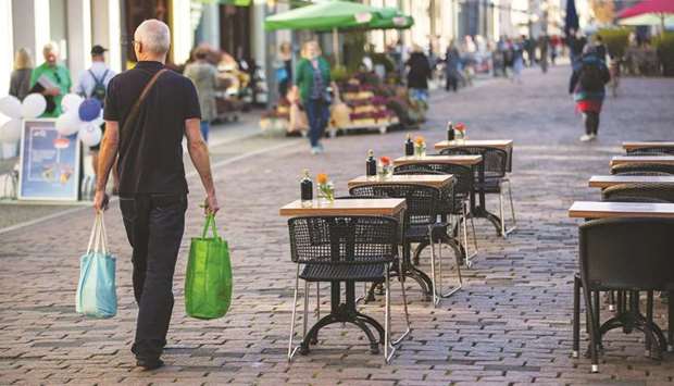 A shopper passes vacant terrace tables and chairs outside a cafe in Potsdam, Germany. Federal statistics agency Destatis said the rebound in July to September, coming after a historic slump in the second quarter, was driven by u201chigher final consumption expenditure of households, higher capital formation in machinery and equipment and a sharp increase in exportsu201d.